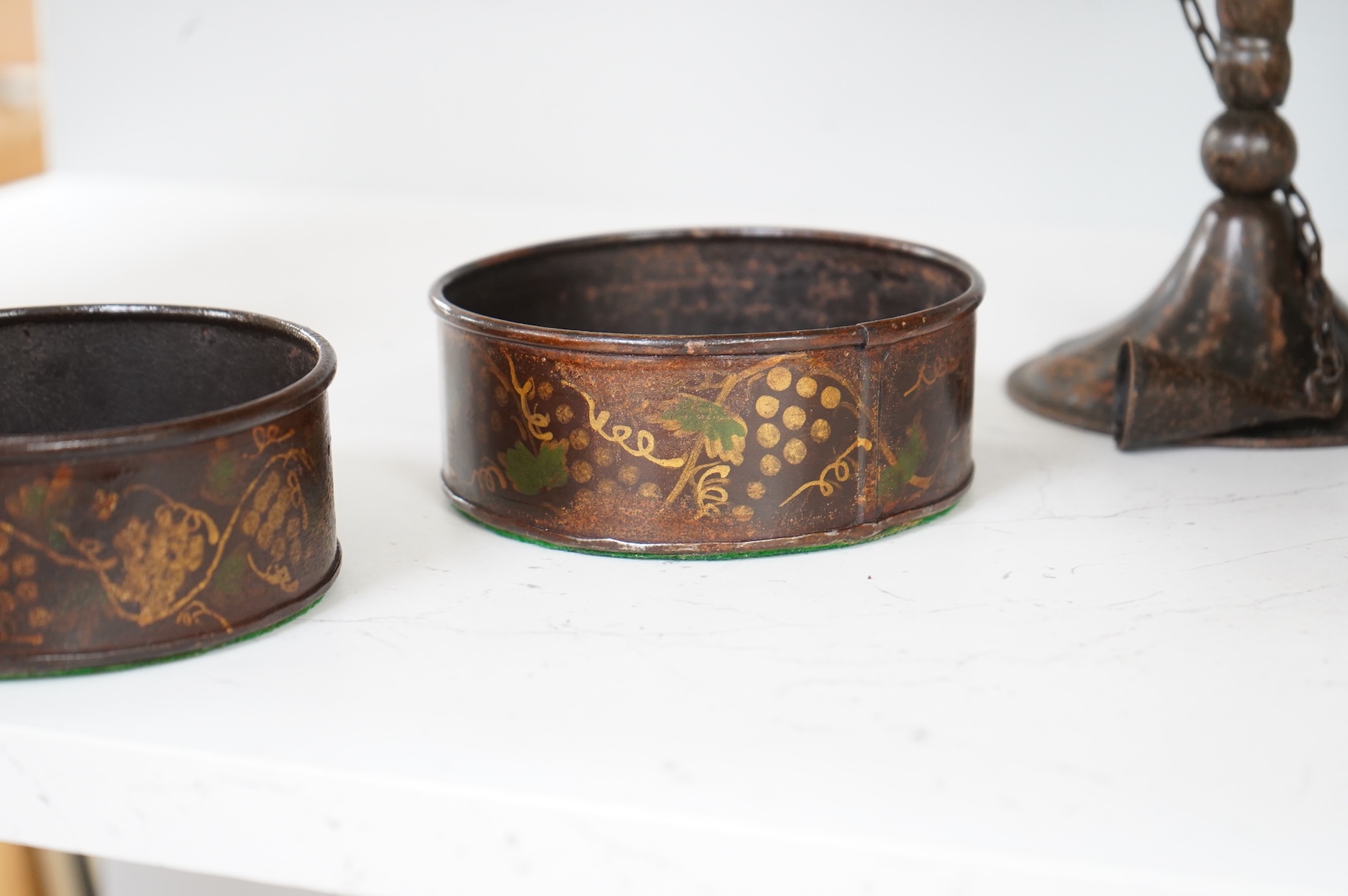 A pair of 19th century toleware wine coasters and an Arts & Crafts iron candlestick with attached snuffer, 21cm high